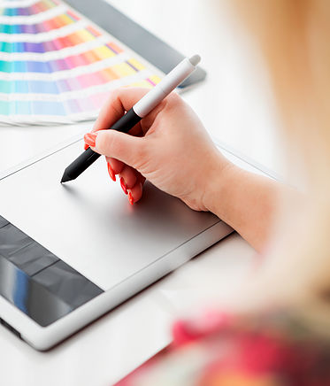Graphic designer working on a digital tablet in the background with pantone palette